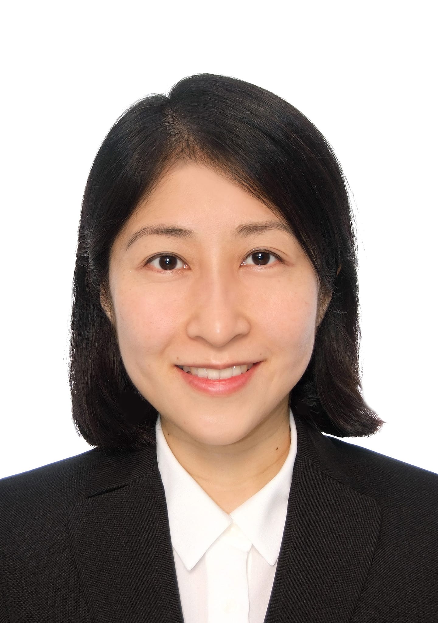 Headshot of a woman with dark hair, wearing a black suit and white collared shirt.